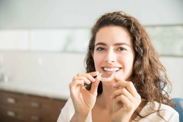 Woman with straight teeth putting in retainer Retainers